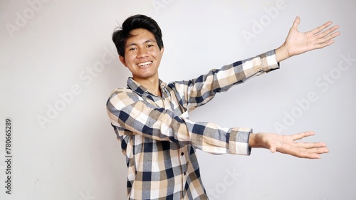 happy young asian man posing showing copy space on the side with both hands