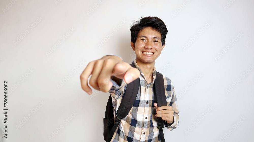 happy young asian man posing pointing forward and holding bag happy young asian man posing pointing forward and holding bag