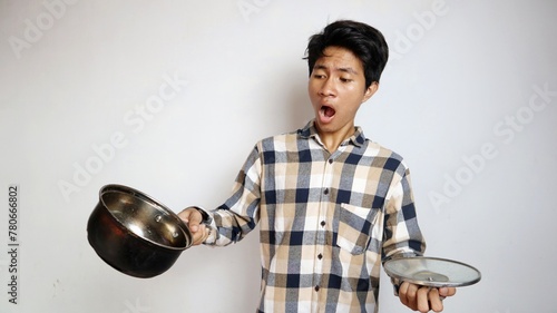 shocked young Asian man posing holding a pan