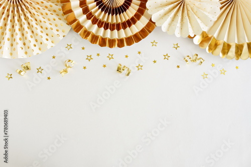 Birthday background template mock up  top view with golden fan paper decor and gold stars confetti on white backdrop. Copy space. Holiday, wedding, party background.