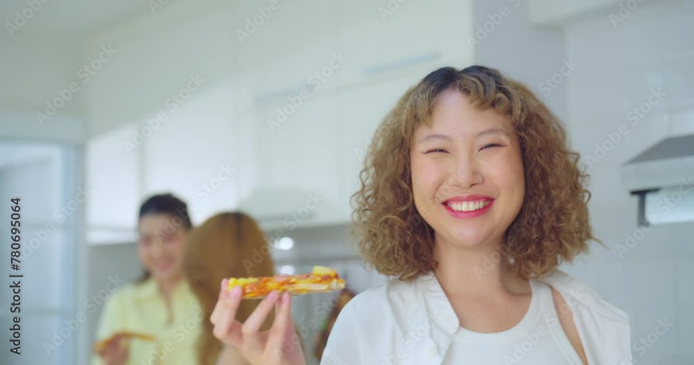 Cheerful woman with a bright smile holding a slice of pizza, with friends in the background. Cheerful woman with a bright smile holding a slice of pizza, with friends in the background.