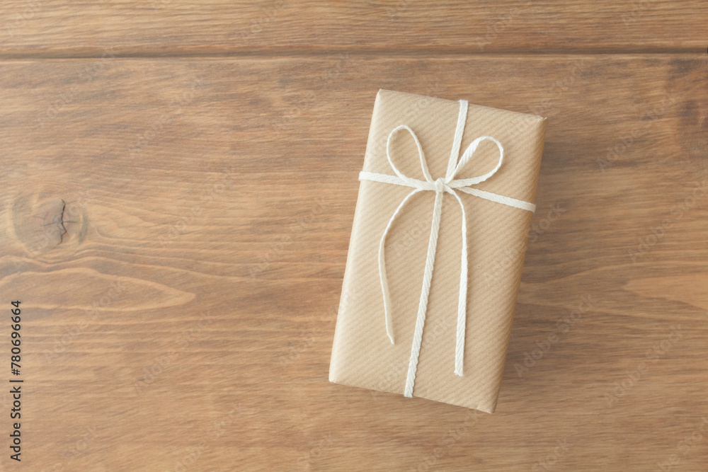 Present wrapped in kraft paper wrapping paper on wooden table seen from overhead
Present wrapped in kraft paper wrapping paper on wooden table seen from overhead
