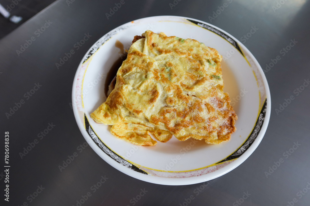 carrot pudding wrapped with fried egg omelette on a white plate on a iron metal table as Taiwanese breakfast carrot pudding wrapped with fried egg omelette on a white plate on a iron metal table as Taiwanese breakfast