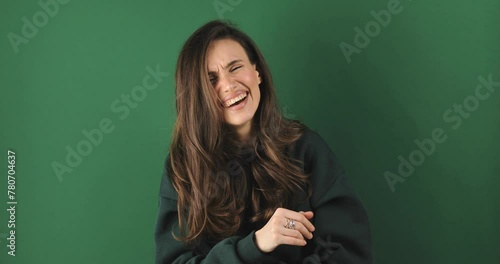 Young excited cheerful funny brunette woman look camera laugh smiling watch comedy movie, listening joke, pointing index finger on you isolated on green background studio portrait.
