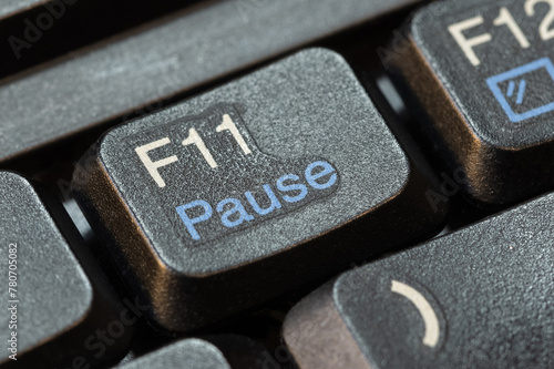 Macro, extreme closeup detail of an f11 pause key on a modern laptop computer keyboard, nobody, no people. Pausing taking a break from work activity symbol simple abstract concept. Relax time, break