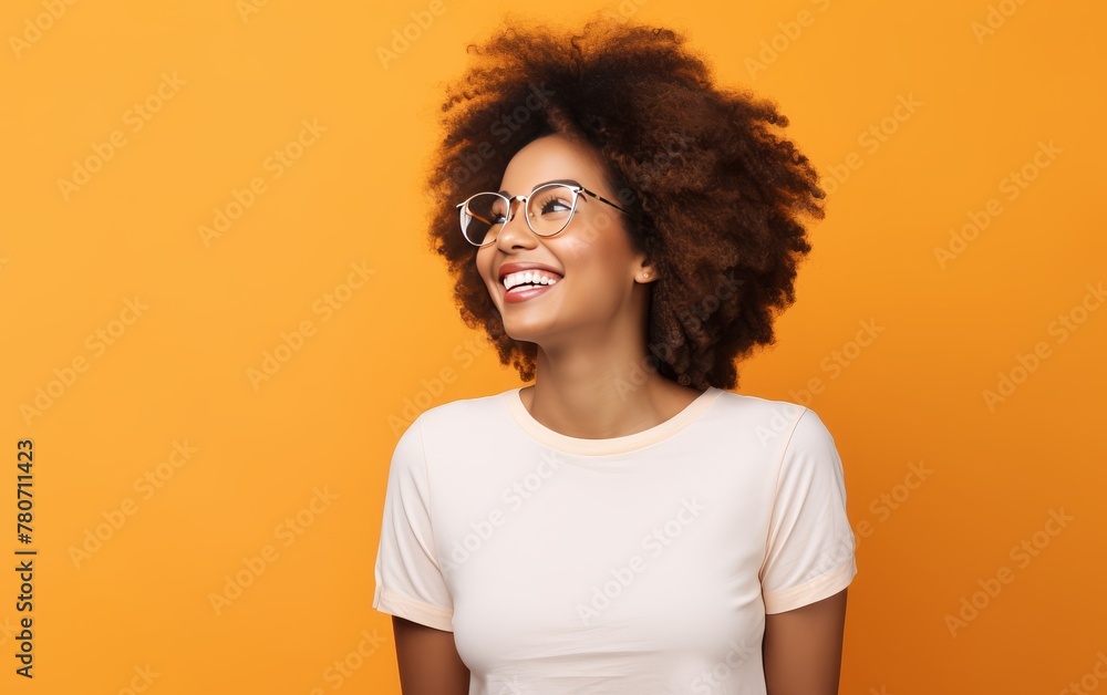 Happy African American woman in glasses smiling and gazing upwards, isolated on a orange backdrop. Happy African American woman in glasses smiling and gazing upwards, isolated on a orange backdrop.