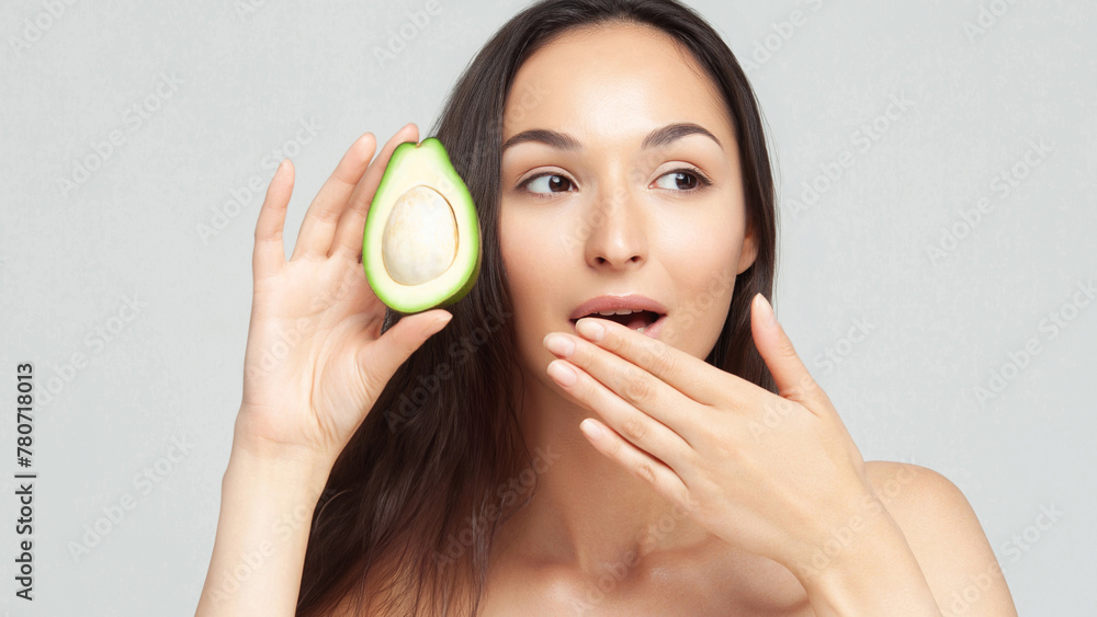 Young beautiful woman holding half an avocado Young beautiful woman holding half an avocado