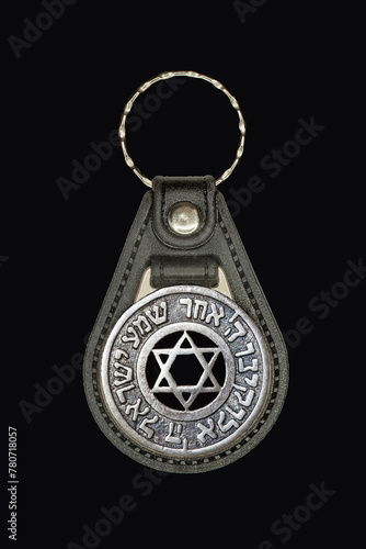 Brown leather key ring with chrome ring and silver plate with Star of David and Shema Israel prayer in Hebrew. Isolate on black.