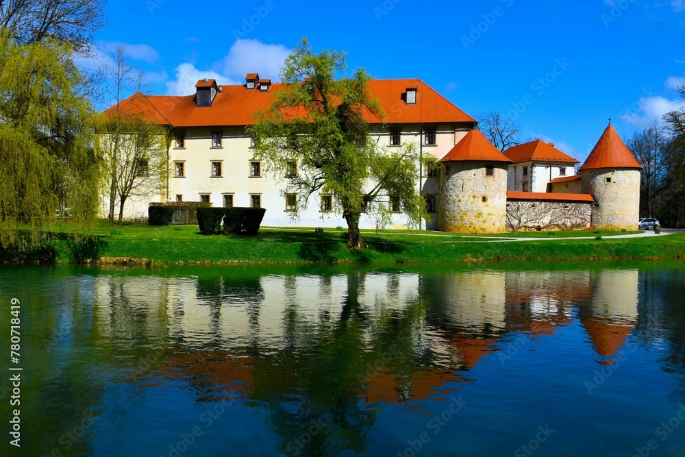 View of Otočec castle and a reflection of the castle in the water of Krka rive in Dolenjska, Slovenia