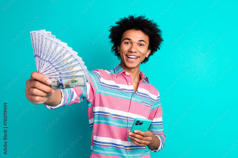Photo of cheerful positive rich man wear stylish clothes hold banknote cash shopping eshop isolated on cyan color background Photo of cheerful positive rich man wear stylish clothes hold banknote cash shopping eshop isolated on cyan color background