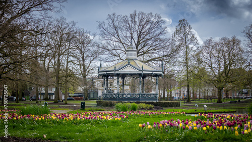 The city park in Apeldoorn called Orange Park, in early spring with blooming multicolored tulips and a pavilion in use  for music and performances in the background, the Netherlands