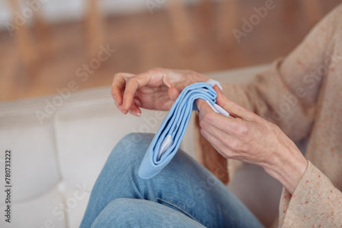 A woman sitting on the floor and putting on white cozy cotton socks on her feet