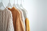 A row of sweaters hanging on a rack, including a yellow one. The sweaters are all knitted and have a cozy, warm feeling
