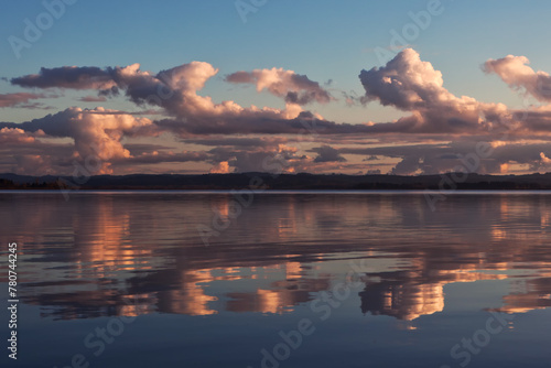 Sunset colored stormy clouds mirrored in the still water of a lake in western Oregon
