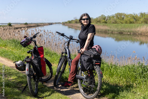 Obraz na płótnie Woman cycles on an e-bike through the Po Delta in Northern Italy w salonie