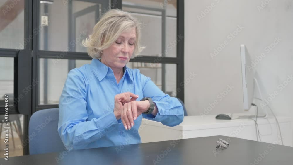 Senior Old Woman Using Smartwatch while Sitting in Office Senior Old Woman Using Smartwatch while Sitting in Office