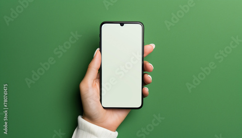 Hand holding blank smartphone on green background