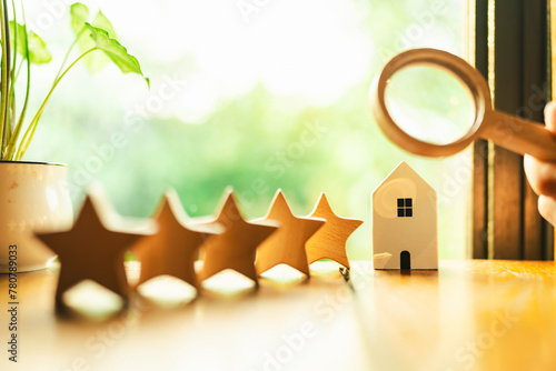 Real estate businessman holding a magnifying glass. To find a quality home, both the land and the house, for a worthwhile investment with the 5 star symbol next to it. photo