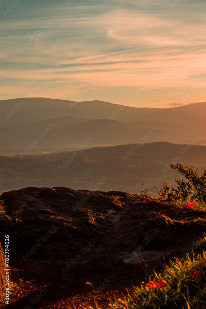 Krajobraz warstw gór ze szczytu Krzyżna Góra w Rudawy Janowickie w letniej odsłonie z widokiem na Karkonosze o zachodzie słońca