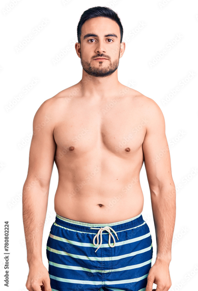 Young handsome man wearing swimwear relaxed with serious expression on face. simple and natural looking at the camera. Young handsome man wearing swimwear relaxed with serious expression on face. simple and natural looking at the camera.