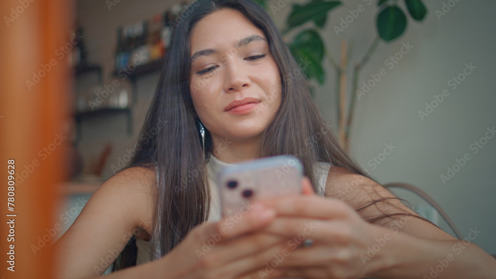 Carefree girl texting smartphone in coffeehouse close up. Asian brunette smiling Carefree girl texting smartphone in coffeehouse close up. Asian brunette smiling