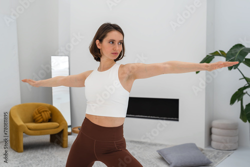 Young woman doing yoga warrior pose during yoga practice at home. Copy space.