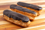 Delicious Cream Filled Chocolate Eclair Pastries on a Wooden Table