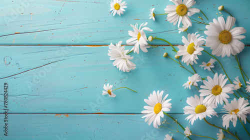 Daisies are scattered across a textured blue wooden surface. © Alena