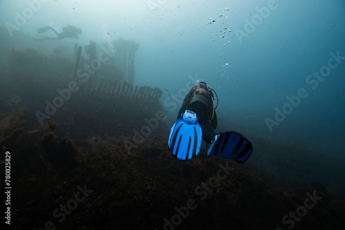 Scuba diver exploring underwater shipwreck in ocean depths photo