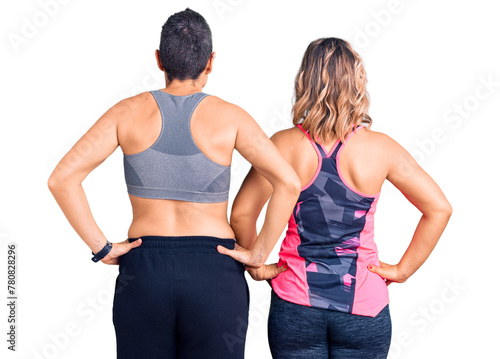 Couple of women wearing sportswear standing backwards looking away with arms on body