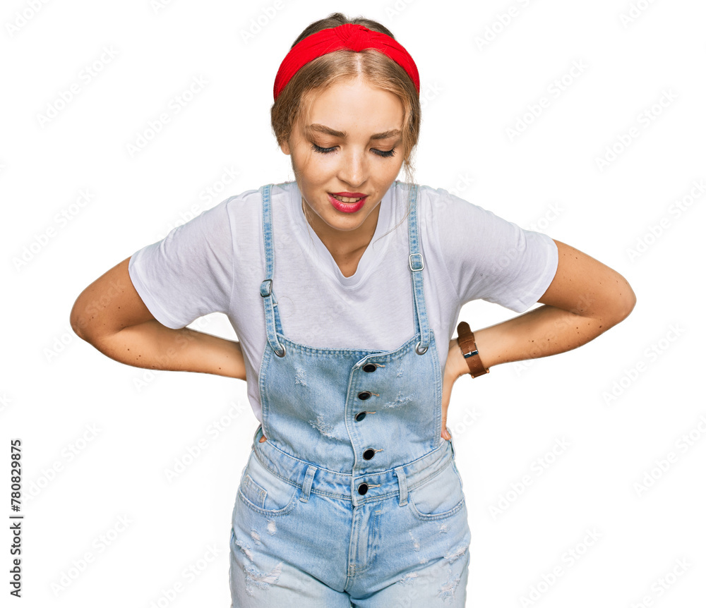 Young caucasian girl wearing casual clothes suffering of backache, touching back with hand, muscular pain Young caucasian girl wearing casual clothes suffering of backache, touching back with hand, muscular pain