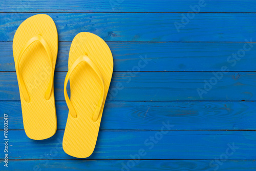 Bright yellow flip-flops on wooden background, top view. Summer concept