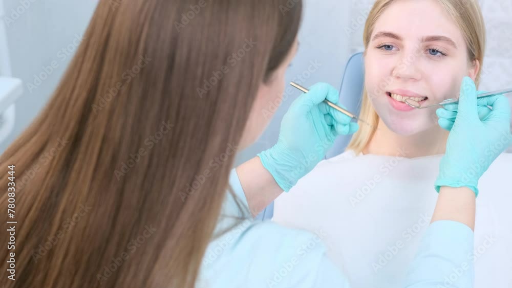 Dentist examines a patients teeth with a dental mirror and probe. Dentist examines a patients teeth with a dental mirror and probe.