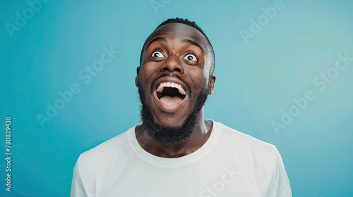 Portrait of a happy and excited man looking up with mouth open on pastel blue background photo