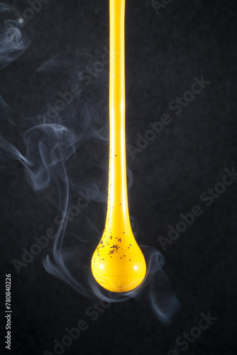 Gota de vidro amarelo semi transparente em fundo preto. Fotografia em close up de uma peça similar a um líquido de alta viscosidade pingando com fundo de efeito especial de cenário neutro. photo