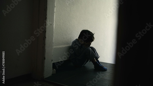 Sad and Lonely Young Child Sitting in Dark Hallway, Hiding Face in Hands, Symbolizing Emotional Distress and Family Turmoil