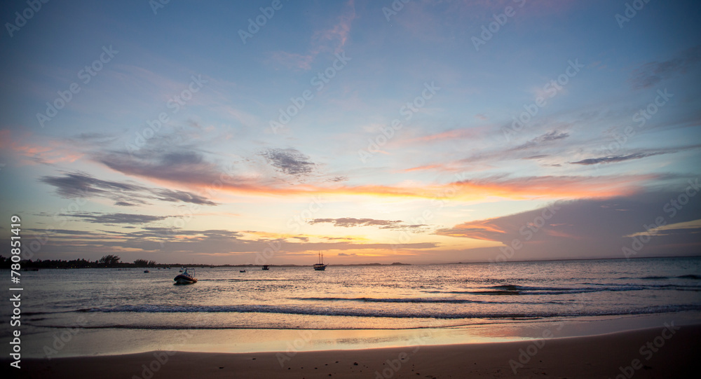 Fototapeta premium Pôr-do-sol na linha do mar, com barcos e navios no horizonte e degradê colorido de nuvens no nordeste brasileiro. Céu alaranjado e roxo. 
