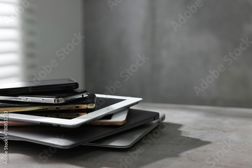 Many different modern gadgets on grey table indoors. Space for text