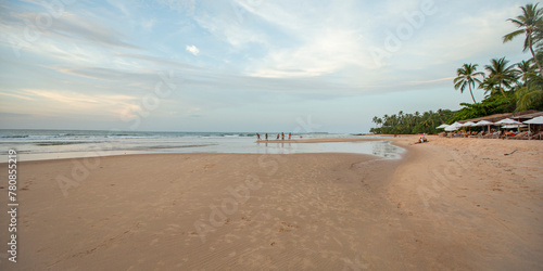 Fototapeta Naklejka Na Ścianę i Meble -  Praia do nordeste brasileiro com banhistas e luz suave de entardecer. Amigos jogando futebol na areia
