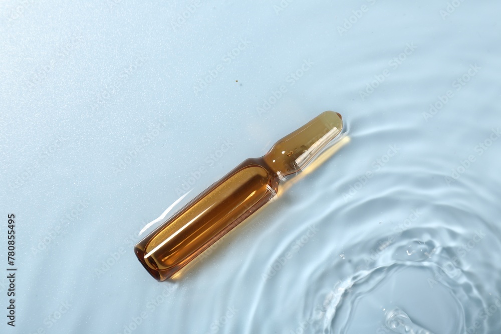 Naklejka premium Skincare ampoule in water on light blue background, top view