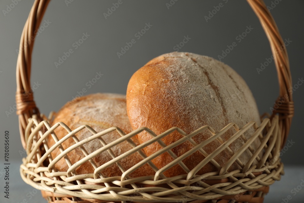 Wicker basket with fresh bread on grey table, closeup
