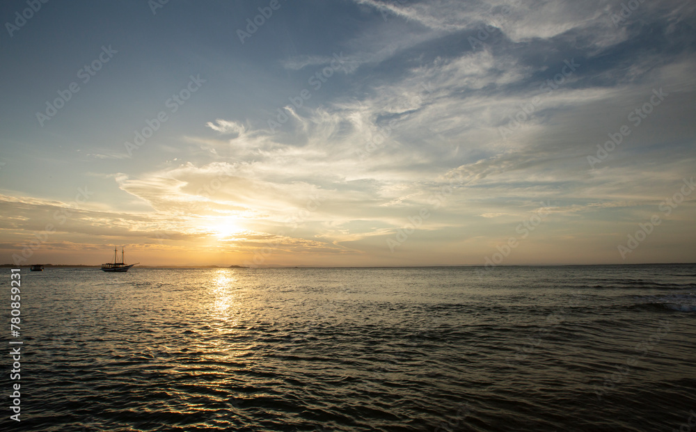 Sol na linha do mar com barcos em um pôr-do-sol no nordeste brasileiro