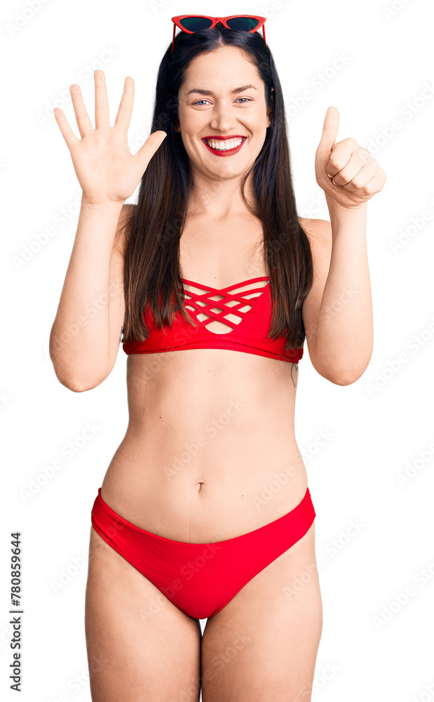 Young beautiful caucasian woman wearing bikini showing and pointing up with fingers number six while smiling confident and happy. Young beautiful caucasian woman wearing bikini showing and pointing up with fingers number six while smiling confident and happy.