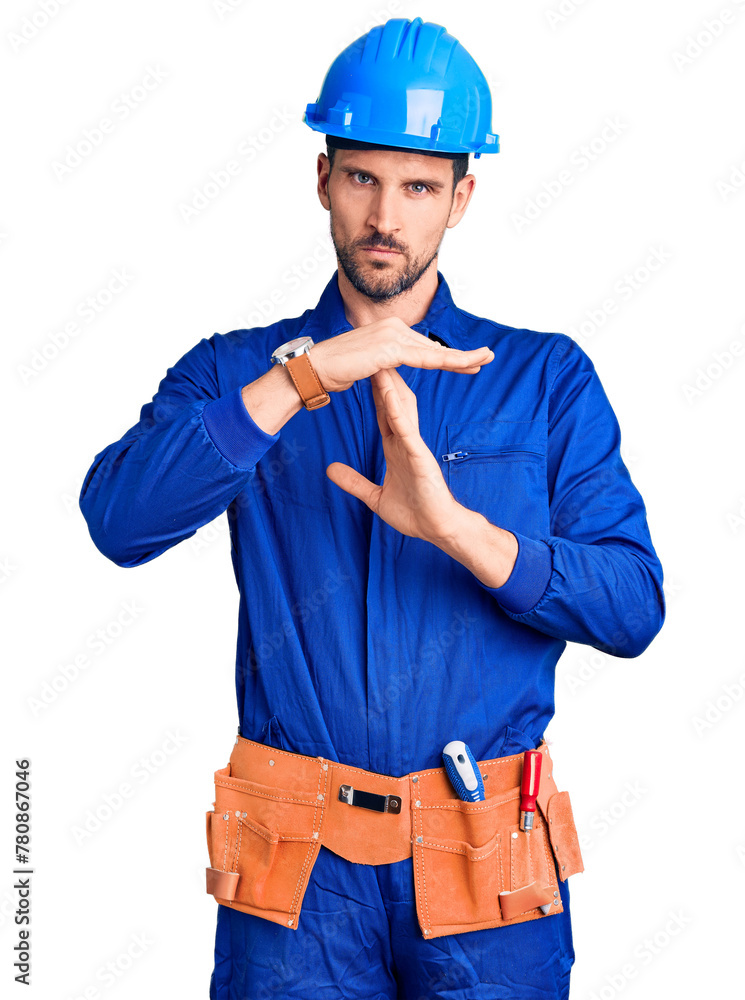 Young handsome man wearing worker uniform and hardhat showing middle finger, impolite and rude fuck off expression Young handsome man wearing worker uniform and hardhat showing middle finger, impolite and rude fuck off expression