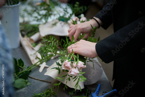 A florist in a flower shop is pruning roses for a flower arrangement