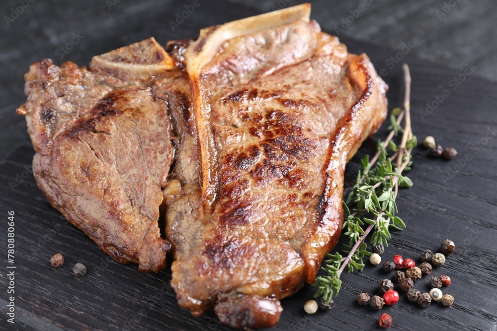 Delicious fried beef meat, thyme and peppercorns on wooden board, closeup Delicious fried beef meat, thyme and peppercorns on wooden board, closeup
