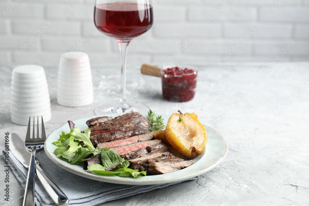Delicious roasted beef meat, caramelized pear and greens served on light table. Space for text Delicious roasted beef meat, caramelized pear and greens served on light table. Space for text