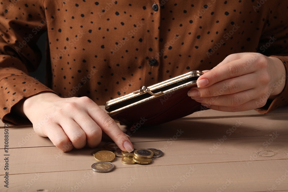 Poverty. Woman with wallet counting coins at wooden table, closeup - obrazy, fototapety, plakaty 