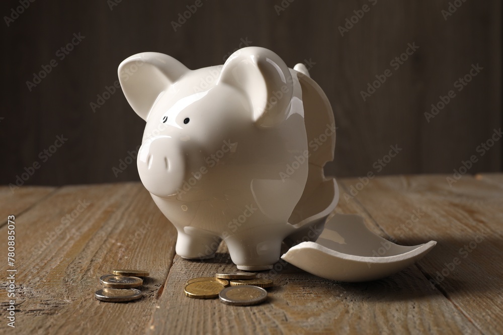 Poverty. Broken piggy bank and coins on wooden table - obrazy, fototapety, plakaty 