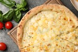 Delicious cheese pizza, basil and tomatoes on dark grey table, flat lay
